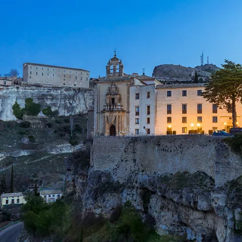 Fachada iluminada al anochecer sobre acantilado.