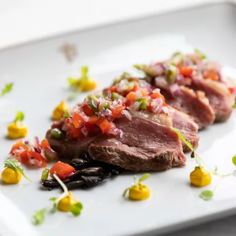 Plato gourmet de carne laminada con guarnición colorida