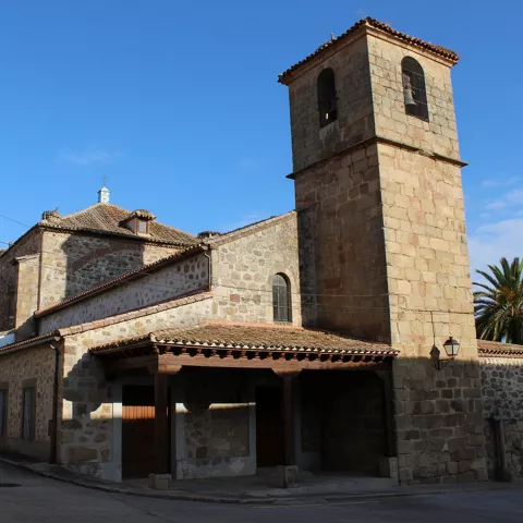 Iglesia de piedra con torre cuadrada y pórtico