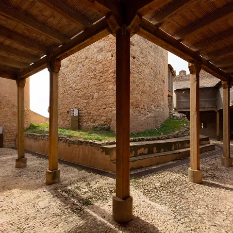 Patio empedrado con galerías de madera y muros antiguos.