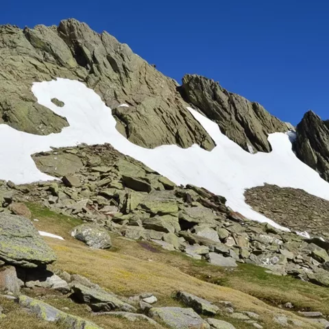 Ladera pedregosa con neveros junto a aristas escarpadas.