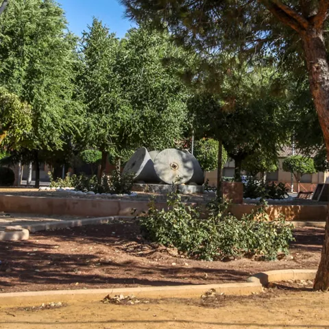 Jardín con piedras de molino y arbolado