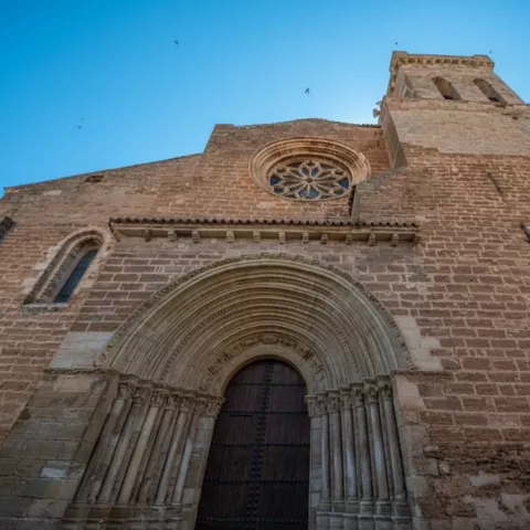 Fachada de templo con rosetón y torre campanario.