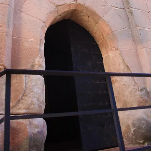 Entrada con arco de piedra y puerta oscura entreabierta.