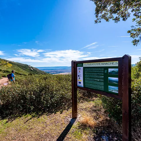 Sendero de montaña con vegetación baja y vistas amplias.
