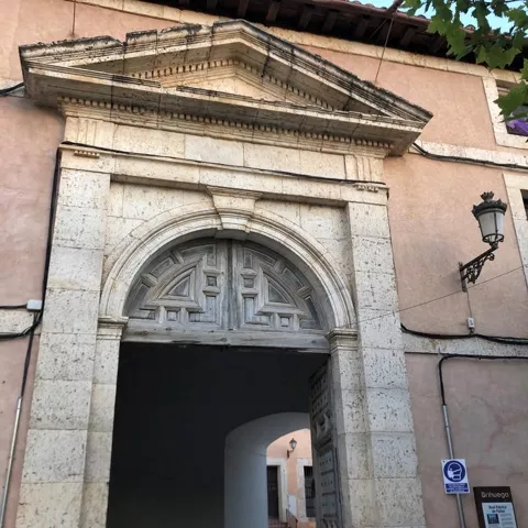 Portalón de piedra con arco clásico y puerta abierta hacia un patio interior.