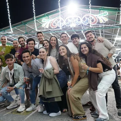 Grupo de jóvenes posa en una feria iluminada de noche