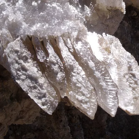 Detalle de cristales de sal brillando sobre roca oscura.
