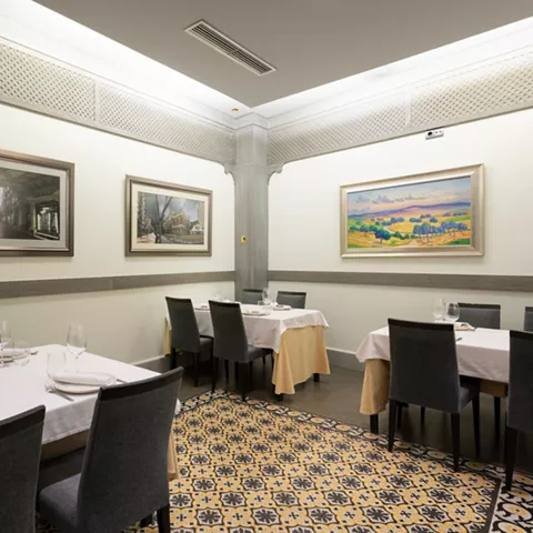 Sala elegante con mesas vestidas y cuadros en pared