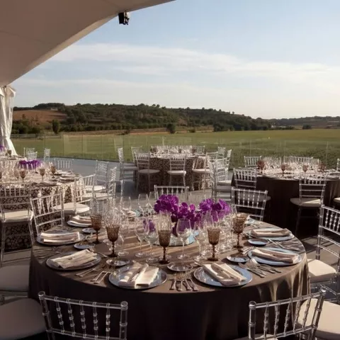 Montaje de banquete al aire libre con mesas redondas, flores y vistas a campos abiertos.