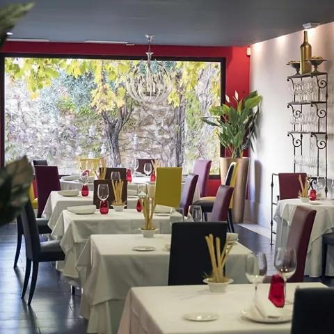 Salón elegante con mesas vestidas y gran ventana al jardín.