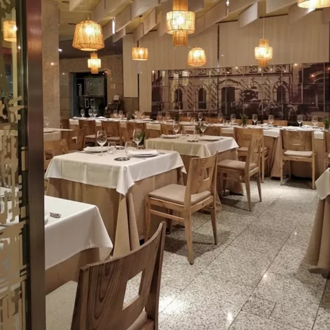 Interior elegante con lámparas colgantes y mesas con manteles blancos.