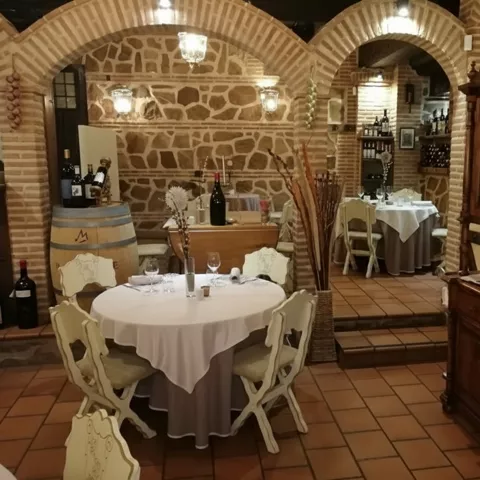 Restaurante tradicional con vigas de madera, paredes de piedra y mesas preparadas.