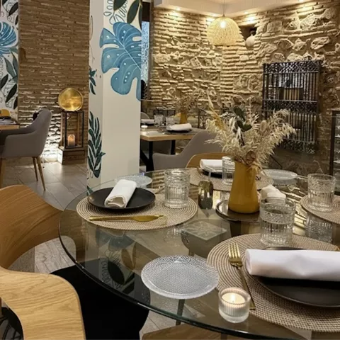 Mesa redonda con vajilla negra junto a columna con motivos vegetales.