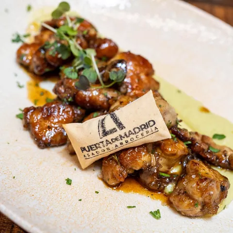 Plato de carne glaseada con hierbas y una oblea decorativa.