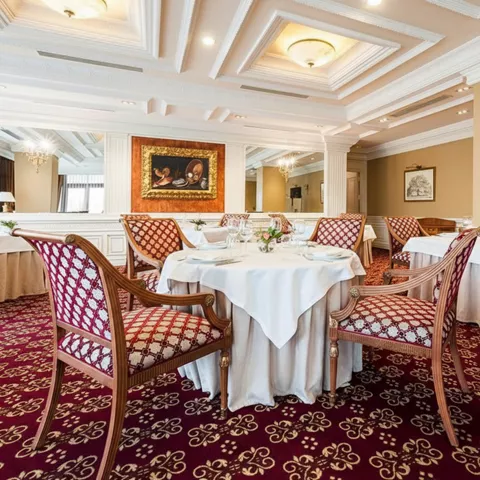 Comedor refinado con moqueta roja estampada y sillas tapizadas en tonos granate.