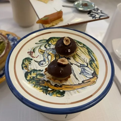 Postres individuales de chocolate presentados en soporte elevado con vajilla decorada.