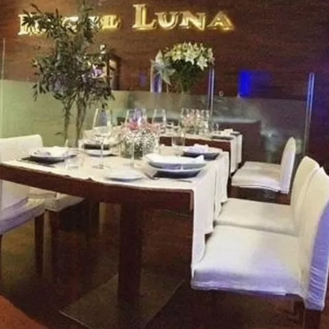 Comedor contemporáneo con mesa alargada, sillas blancas y separadores de cristal.