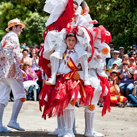 Figura acrobática de baile tradicional levantando a varios niños en el aire.