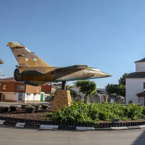 Avión militar expuesto en una rotonda junto a una ermita.
