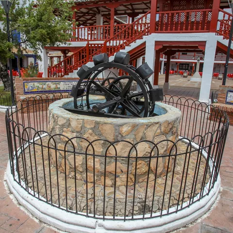 Fuente circular con rueda de molino en plaza porticada