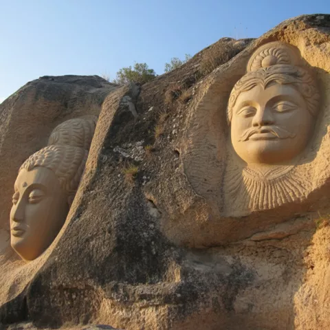 Dos rostros esculpidos en piedra iluminados por el sol