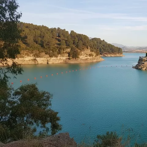 Embalse tranquilo con orillas arboladas y agua azul