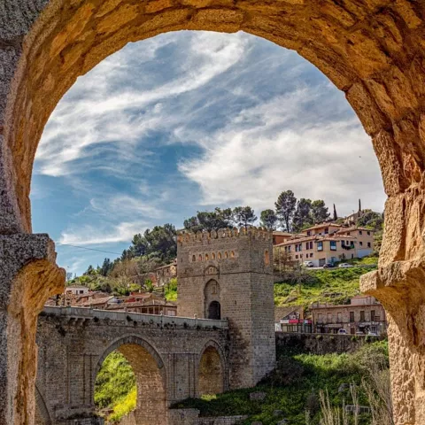 Puente de piedra con torre visto desde un arco