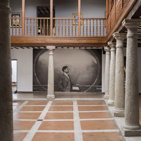 Claustro con columnas de piedra y gran retrato en blanco y negro