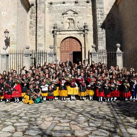 Grupo de personas con vestimenta tradicional frente a iglesia.