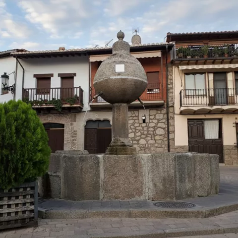 Fuente de piedra frente a fachadas con balcones