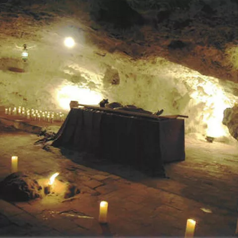 Escena ceremonial en el interior de una cueva iluminada por velas
