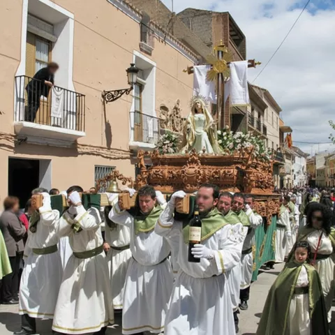 Costaleros portan paso religioso adornado con flores por calle urbana.