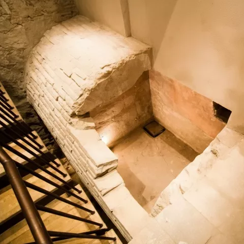 Estructura de ladrillo y piedra con escalones y pequeño espacio excavado en nivel inferior.