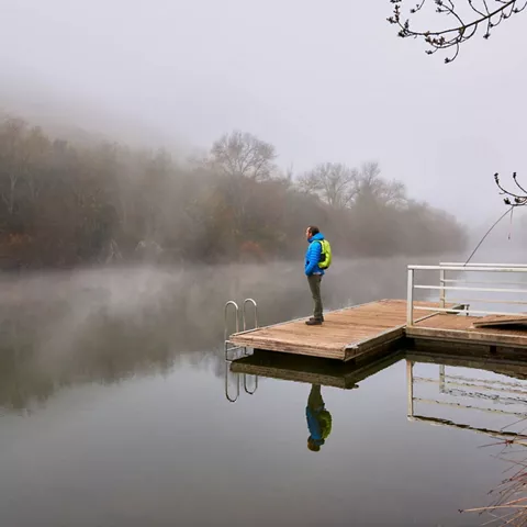 Figura solitaria en embarcadero sobre aguas tranquilas