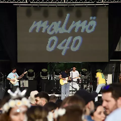 Escenario con banda tocando y público observando desde la zona frontal.