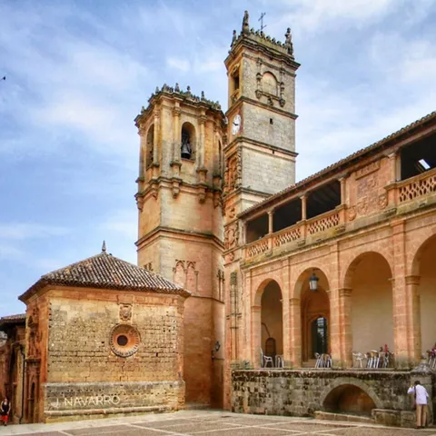 Vista general de un conjunto monumental de piedra con torres y arcadas en una plaza histórica.