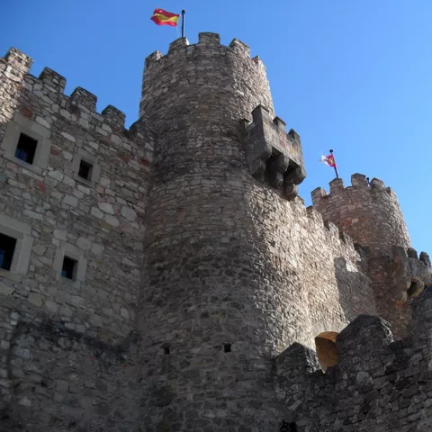 Torres circulares y murallas de piedra bajo cielo azul.