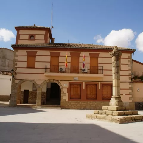 Fachada de edificio institucional con balcón central y plaza abierta