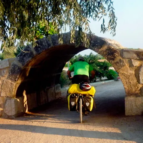 Ciclista atraviesa un pequeño puente de piedra