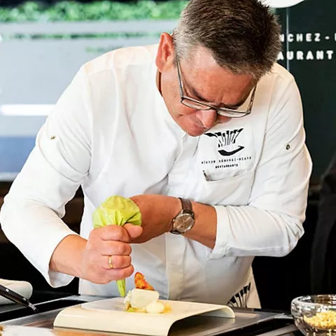 Cocinero emplata un plato con manga pastelera en la cocina
