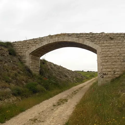 Puente de piedra sobre camino rural.