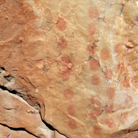 Detalle de roca con puntos rojos agrupados, tipo arte rupestre.