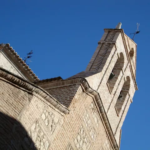Campanario de ladrillo visto desde abajo sobre cielo azul