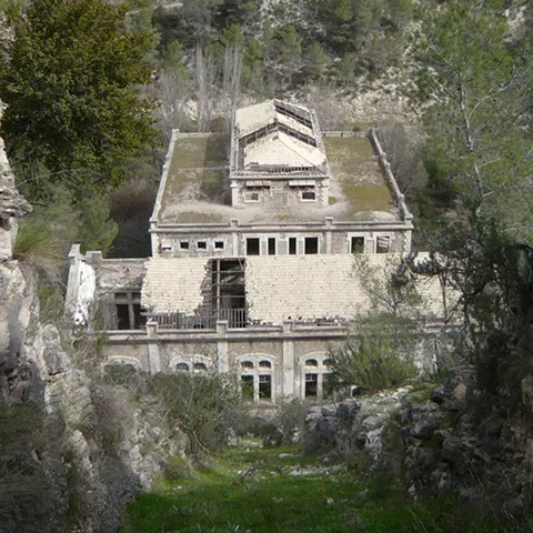 Vista frontal de un edificio en ruinas enmarcado por muros de piedra.