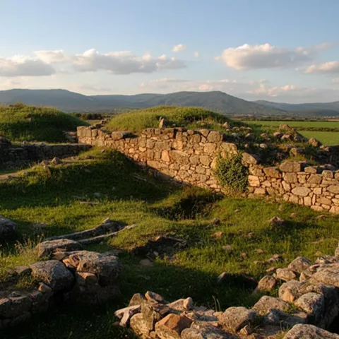 Restos arqueológicos de piedra entre hierba y colinas