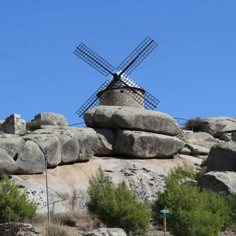 Molino de piedra sobre grandes rocas bajo cielo despejado