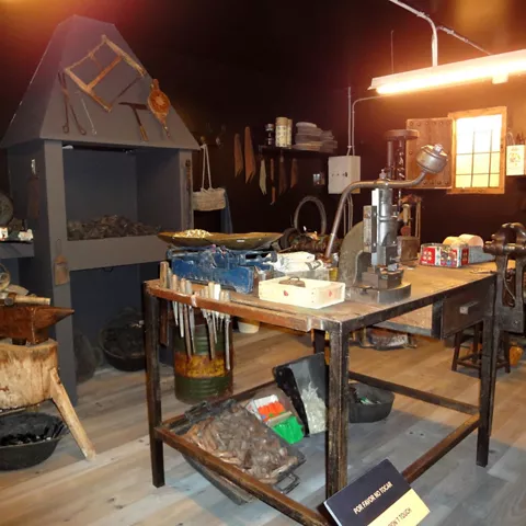 			Recreación de taller tradicional con herramientas, mesa de trabajo y yunque.		