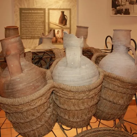 Detalle de grandes cántaros de barro colocados en fundas de esparto trenzado.