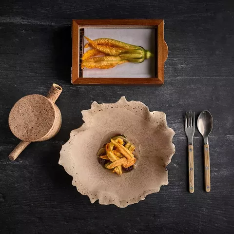 Plato gastronómico presentado sobre vajilla artesanal visto desde arriba.